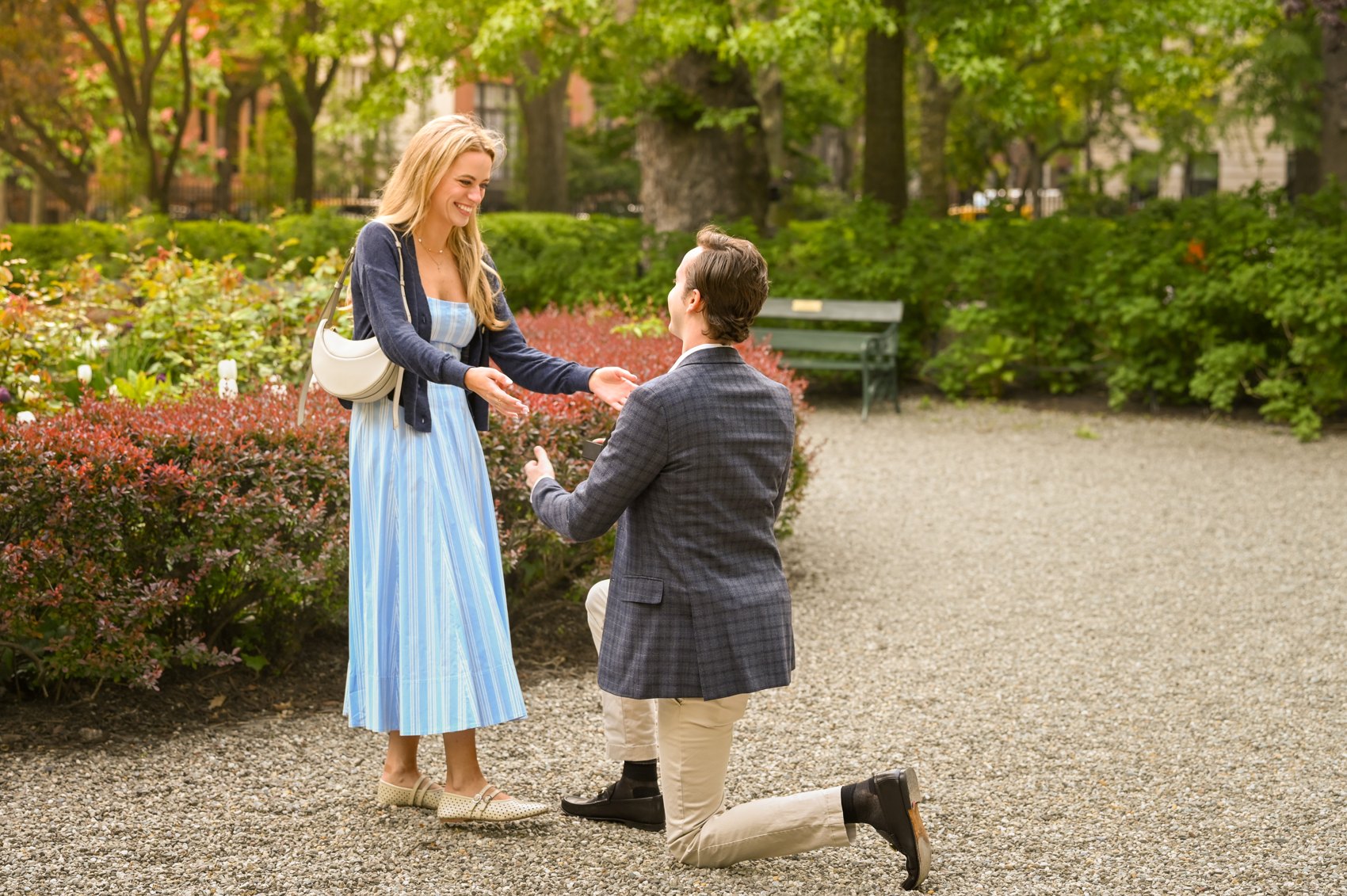 Nick down on one knee proposing, reaching for Kaitlin's hands